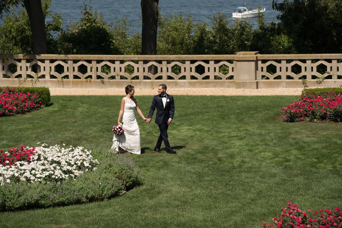 Bride and groom holding hands and walking in the lawn at Hempstead House