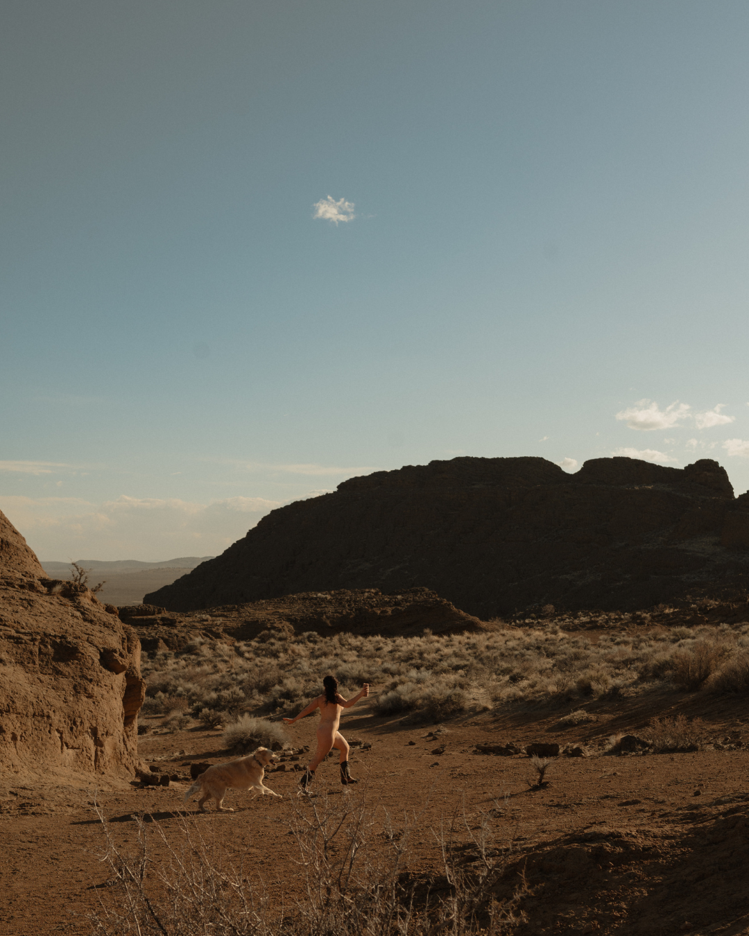 woman and dog run wild and free among the Moab desert landscape on a sunny day