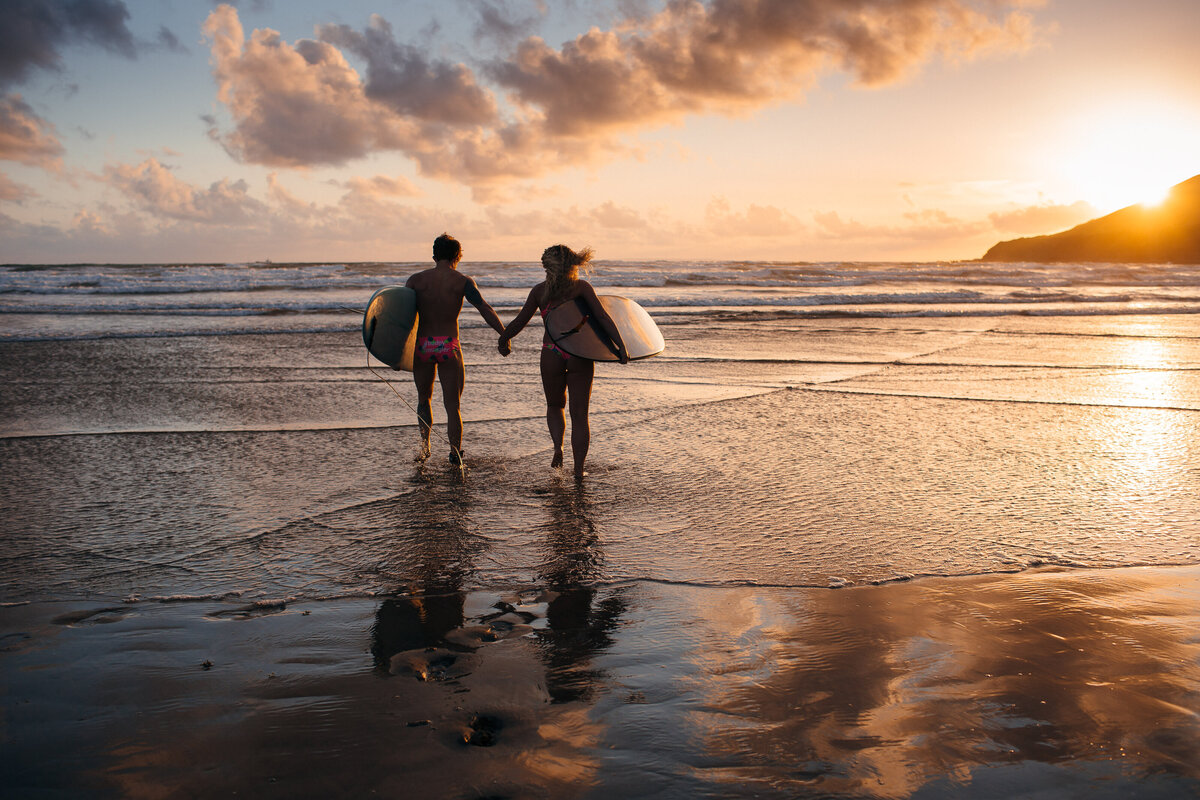 Couple running into the sea with surfboards