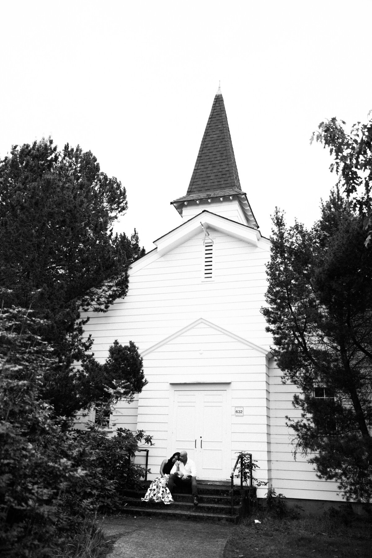 Cute church behind couple at engagement session, in Discovery Park, the best place for romantic engagement photos in Seattle