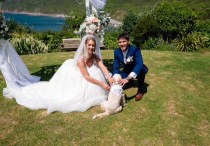 A bride and groom pose for a picture with their dog