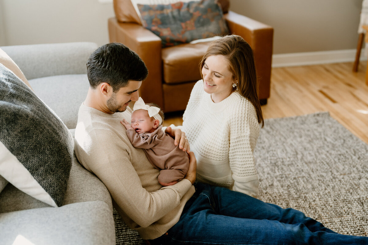 dad holds newborn with mom looking over