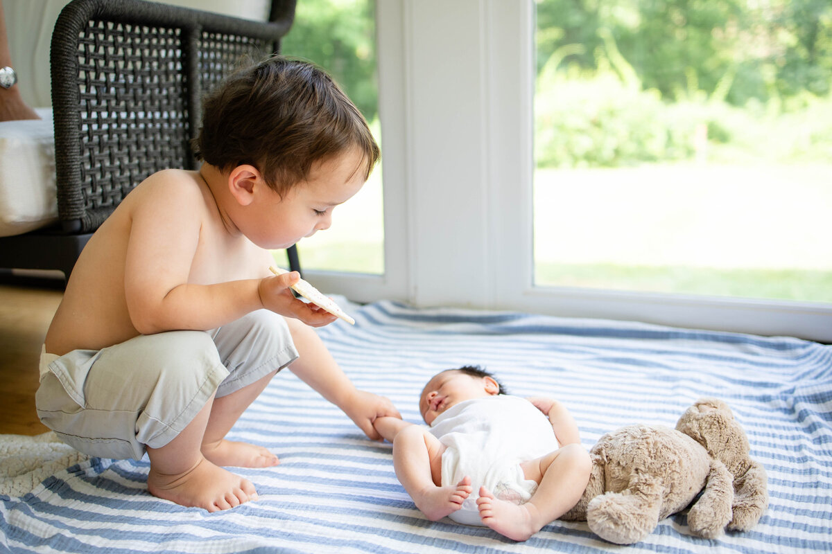 Toddler brother having a snack checking out his newborn brother