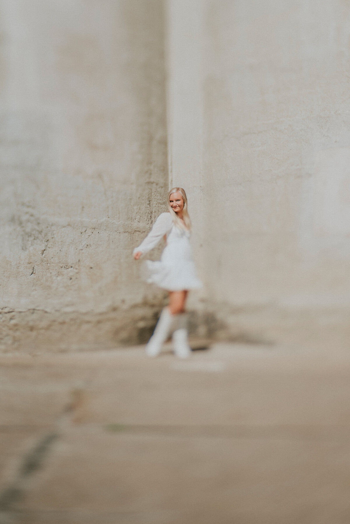 Female dancing in a white dress with a stone wall background in Minneapolis