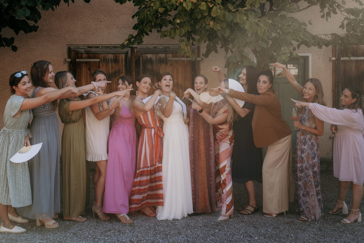Auf diesem Gruppenfoto zeigen alle Freundinnen der Braut fröhlich auf sie.