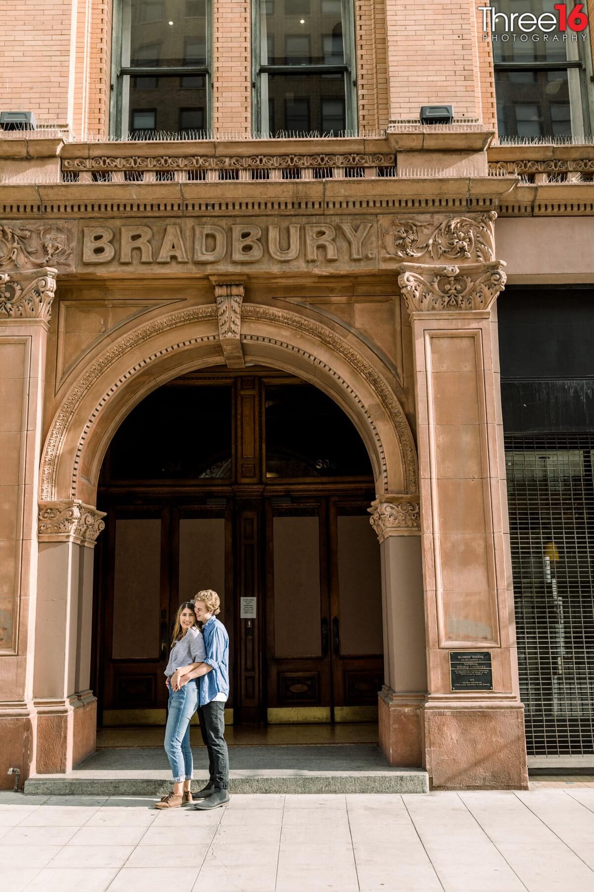 Engaged couple cuddle up in front of the Bradbury Building