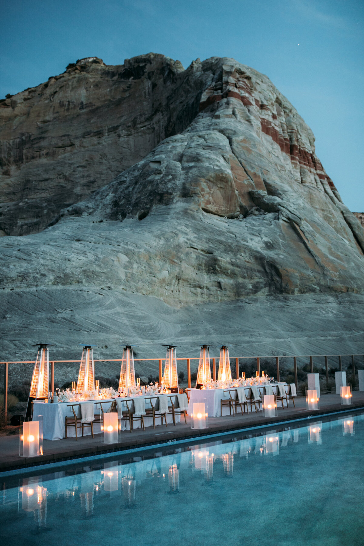 An intimate, candlelit dining setup beside a serene pool, nestled against the dramatic desert landscape of Amangiri.
