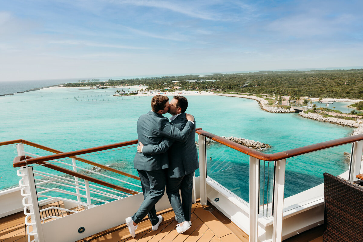 Grooms kissing on deck overlooking castaway cay
