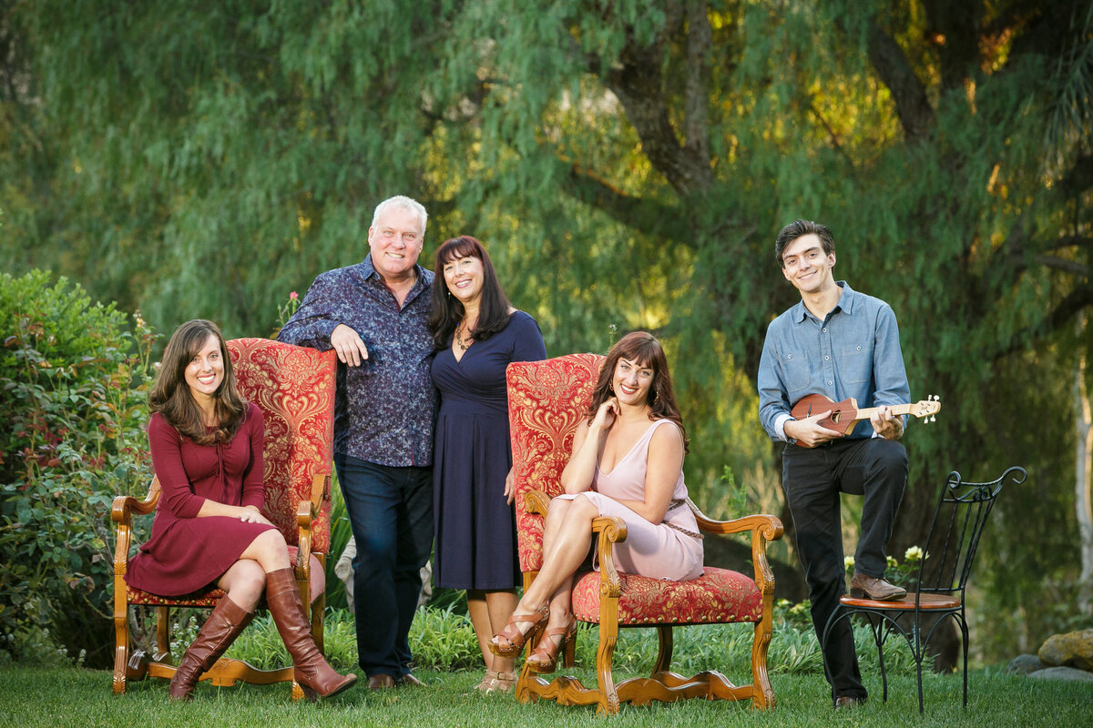 Kids sitting in chairs with their parents standing behind them