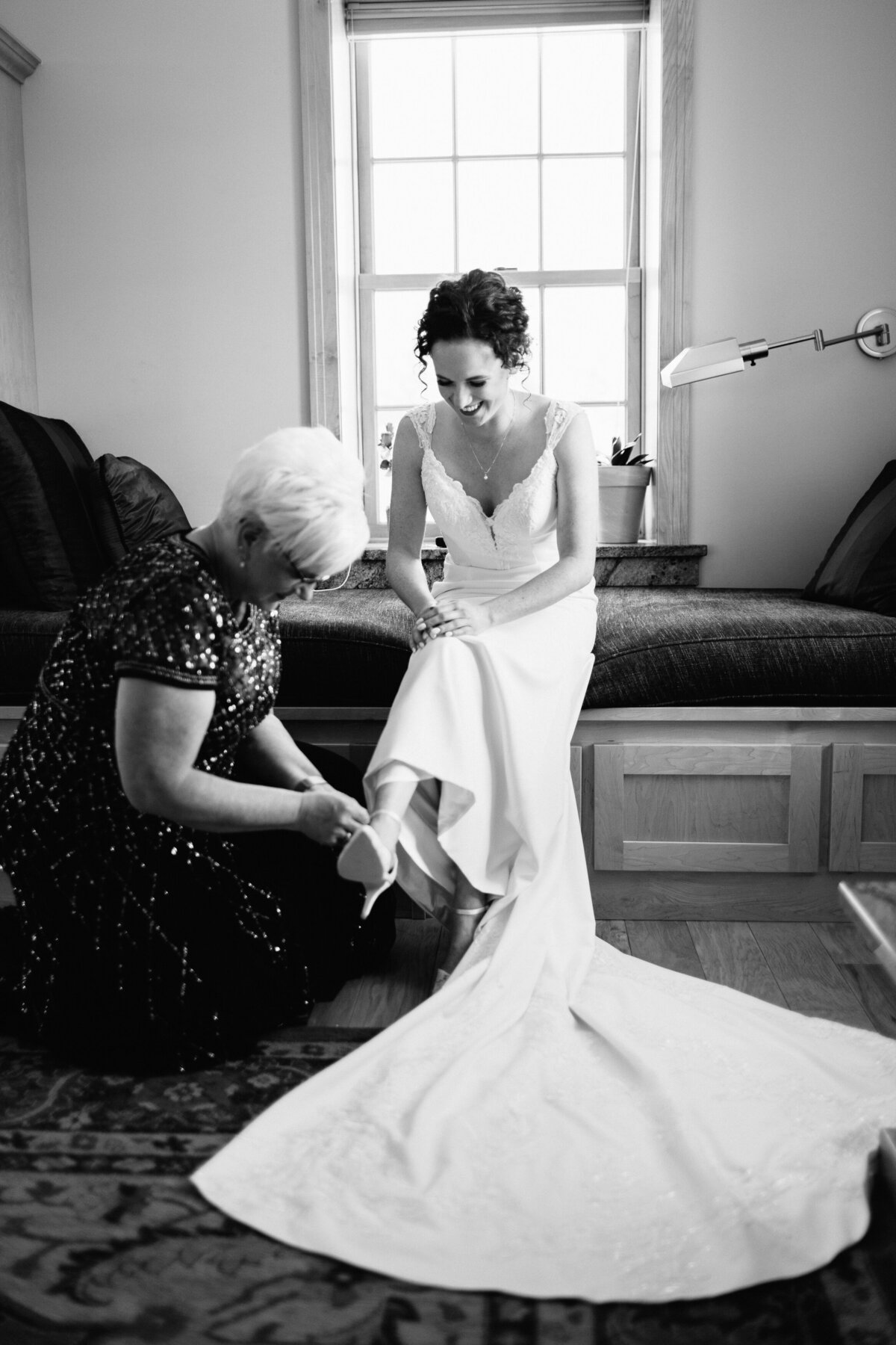 mom helping her daughter with her shoes on her wedding day