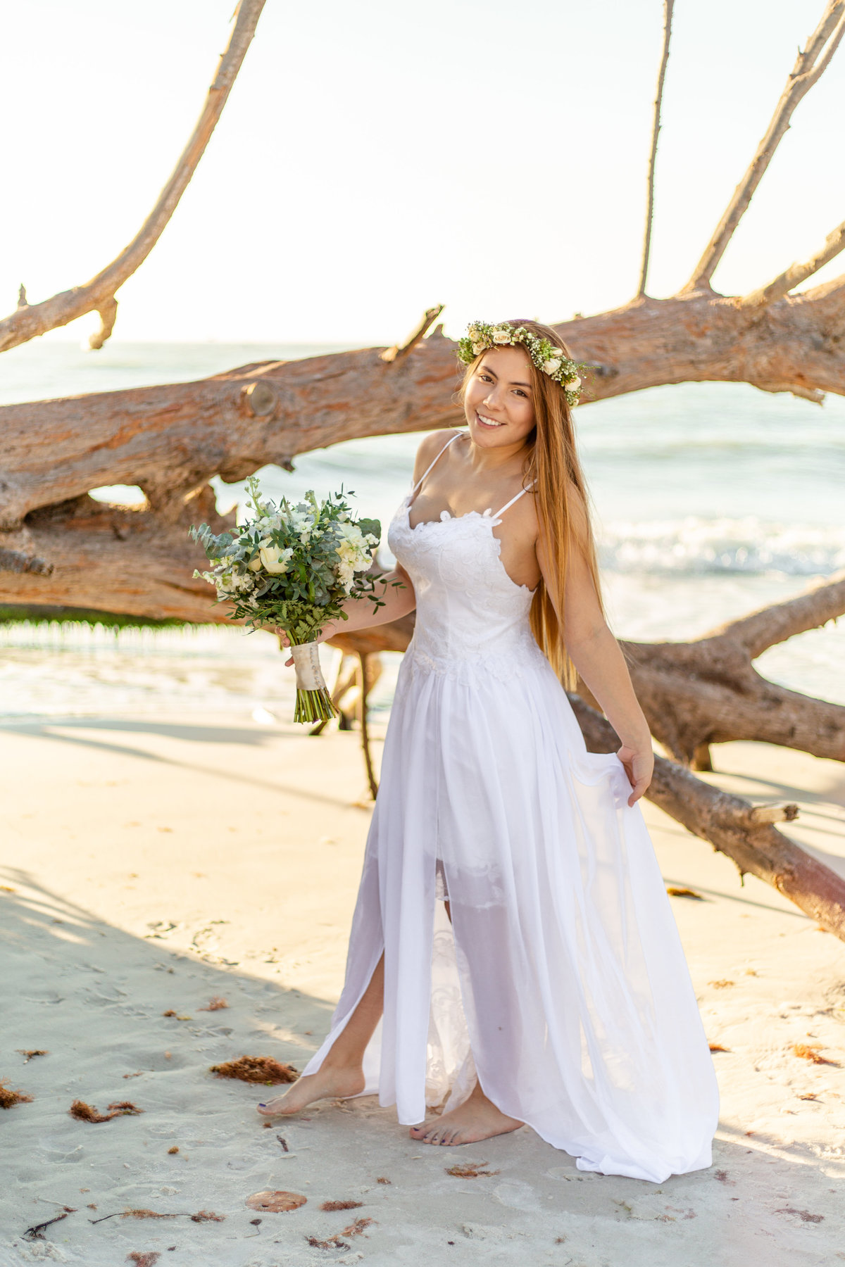 Bride holds green and white bridal bouquet in her white wedding dress at her beach wedding in St. Petersburg, Florida