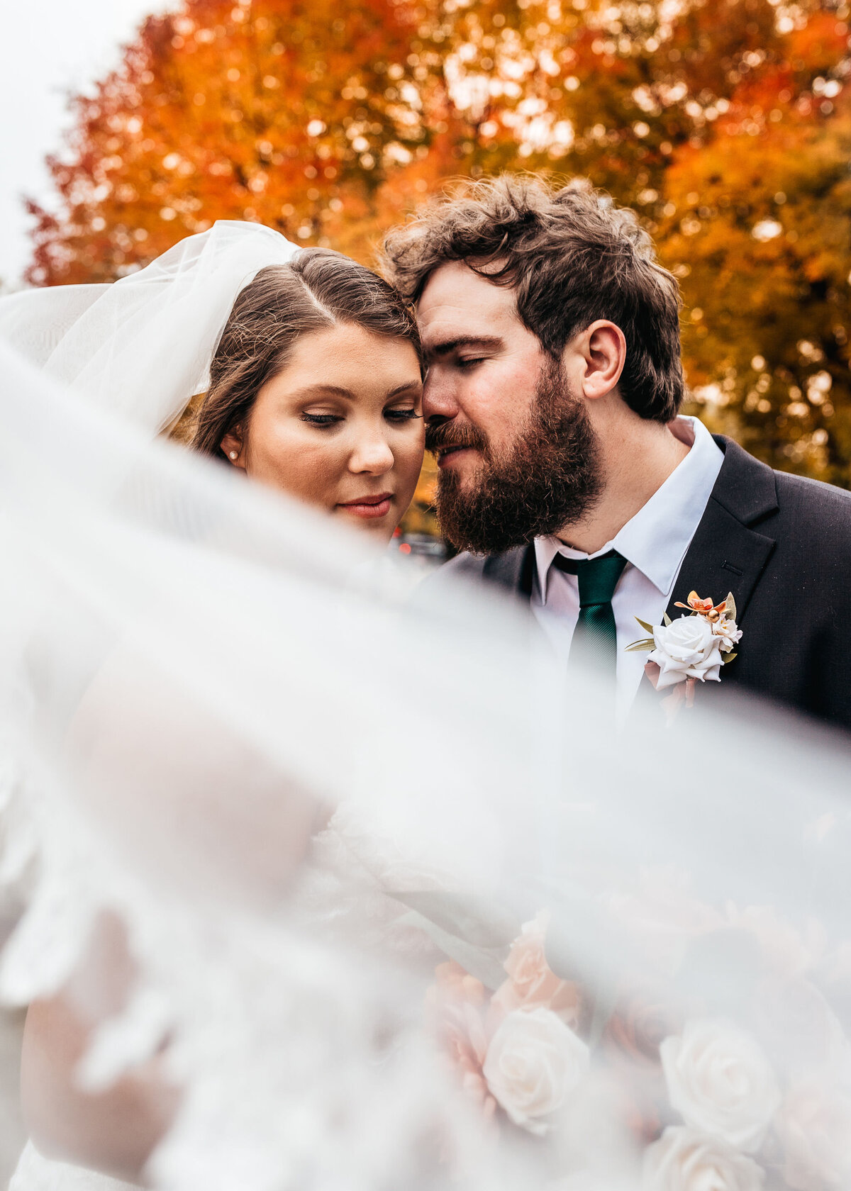 Bridal vail sweeping past couple as they have an intimate moment together in fall wedding at DoubleTree by Hilton hotel in Manchester NH by Lisa Smith Photography