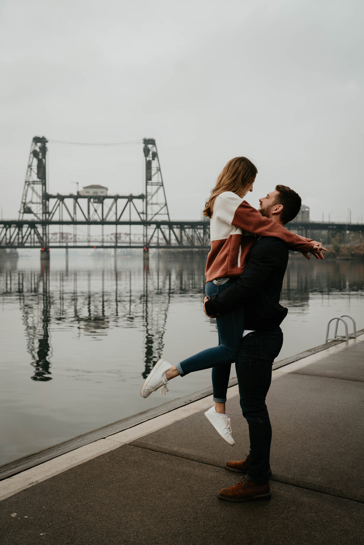 Couple about to kiss in downtown Portland, OR in front of bridge