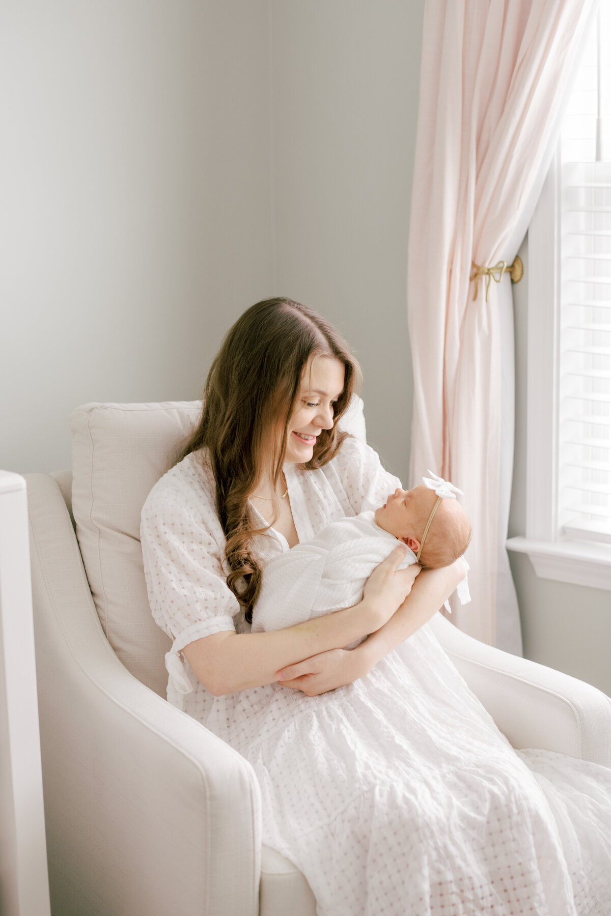 Mom holds her baby and looks down lovingly at her during an in home newborn session in Holly Springs NC. Image by Raleigh newborn photographer A.J. Dunlap Photography.