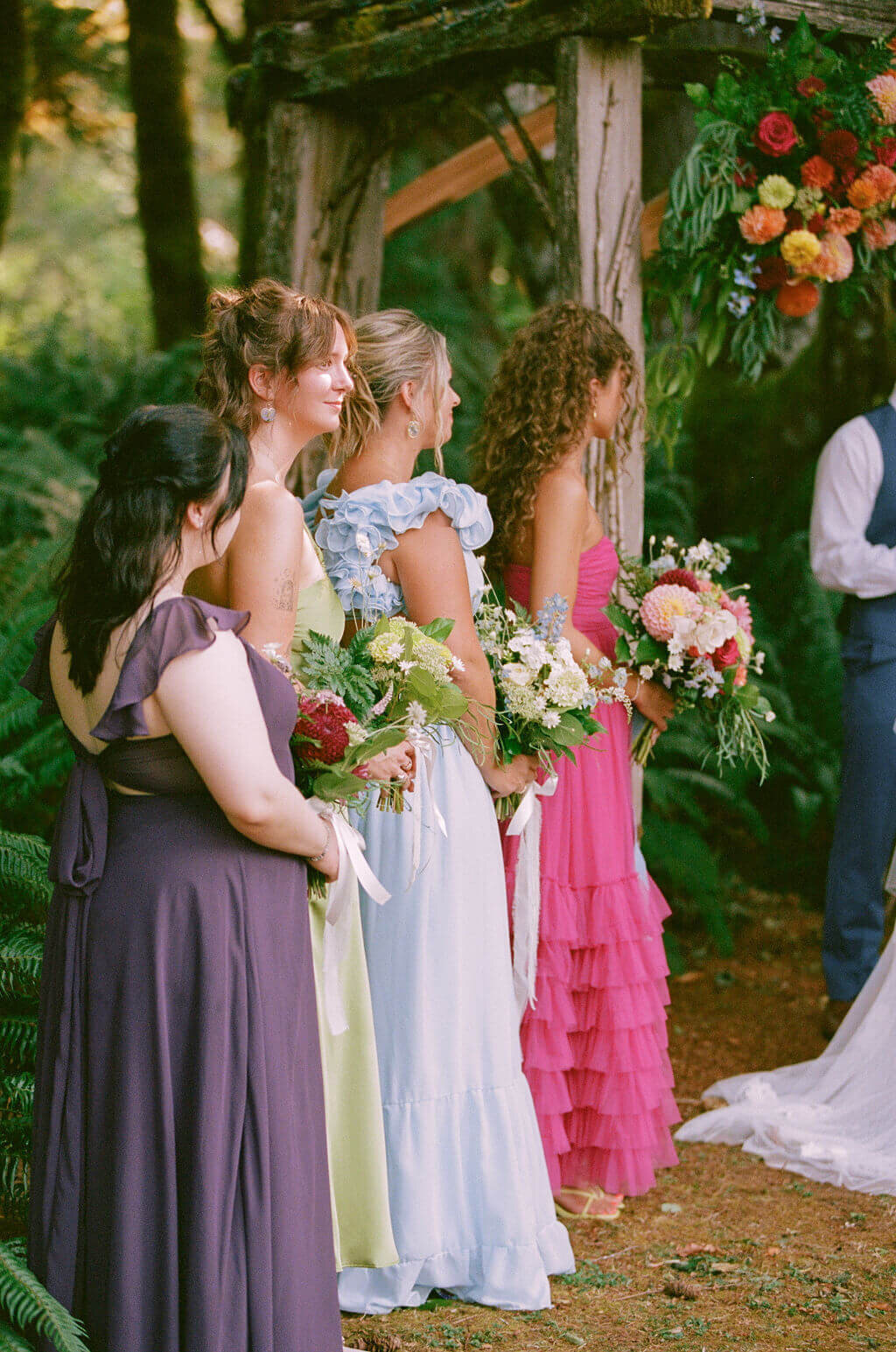 A bridal party in bright dresses stand outdoor at a wedding ceremony at the Thyme Garden Venue in Oregon.