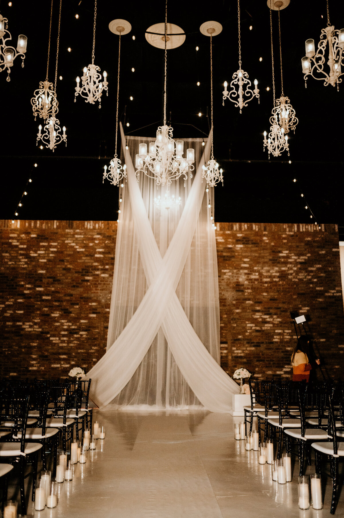 wedding ceremony space with a brick wall, white curtains hanging and white chandeliers in little rock ar