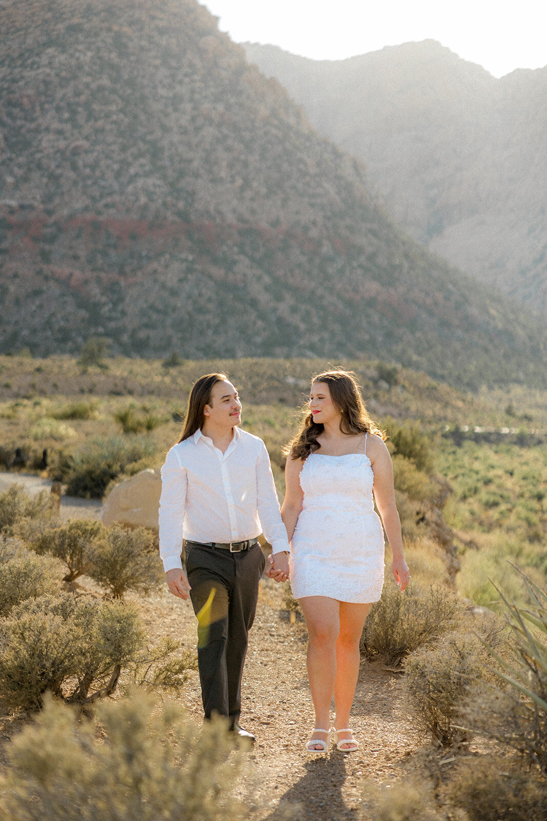 Engaged couple walking with mountains in the background in Nevada
