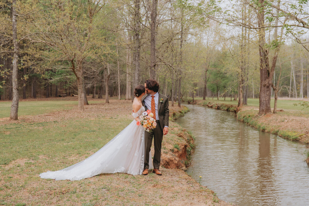 A couple stands outdoors and kisses each other