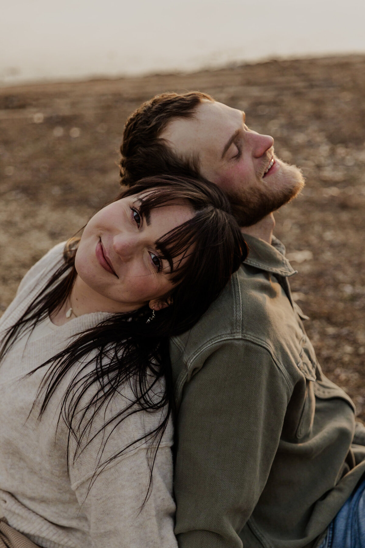 Engaged couple sitting on the ground posing for their engagement session captured by a Minnesota Couples Photographer