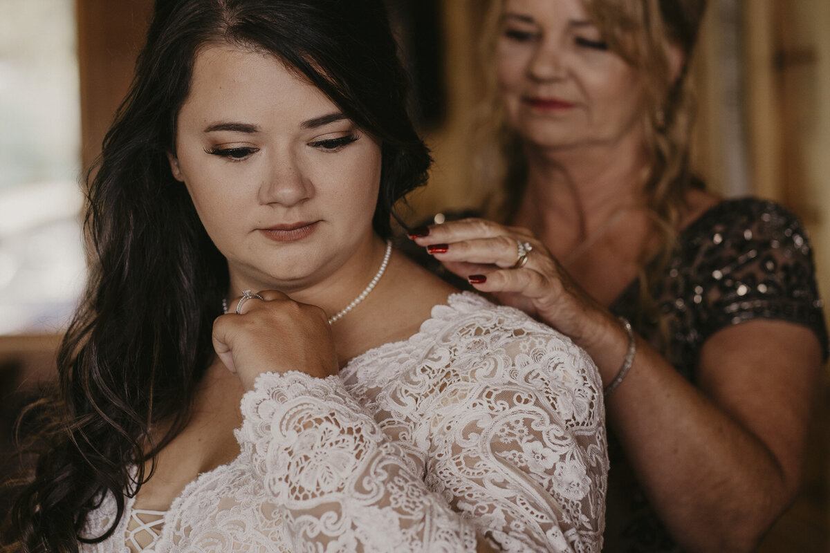 Mother of the bride putting a necklace on bride