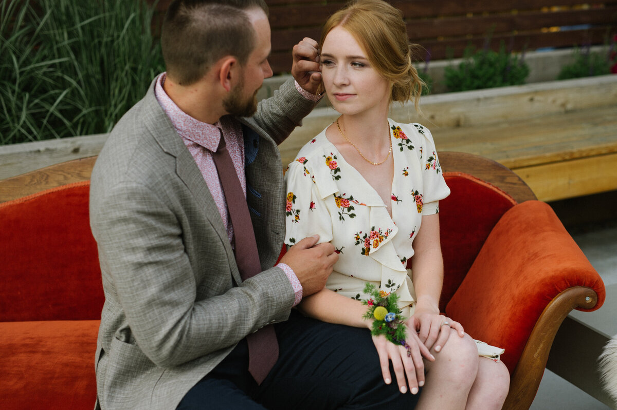 Gorgeous engagement session inspiration, couple on orange sofa, woman in white floral dress, captured by Christy D. Swanberg Photography, editorial elopement and wedding photographer in Calgary, Alberta, featured on the Bronte Bride Vendor Guide.