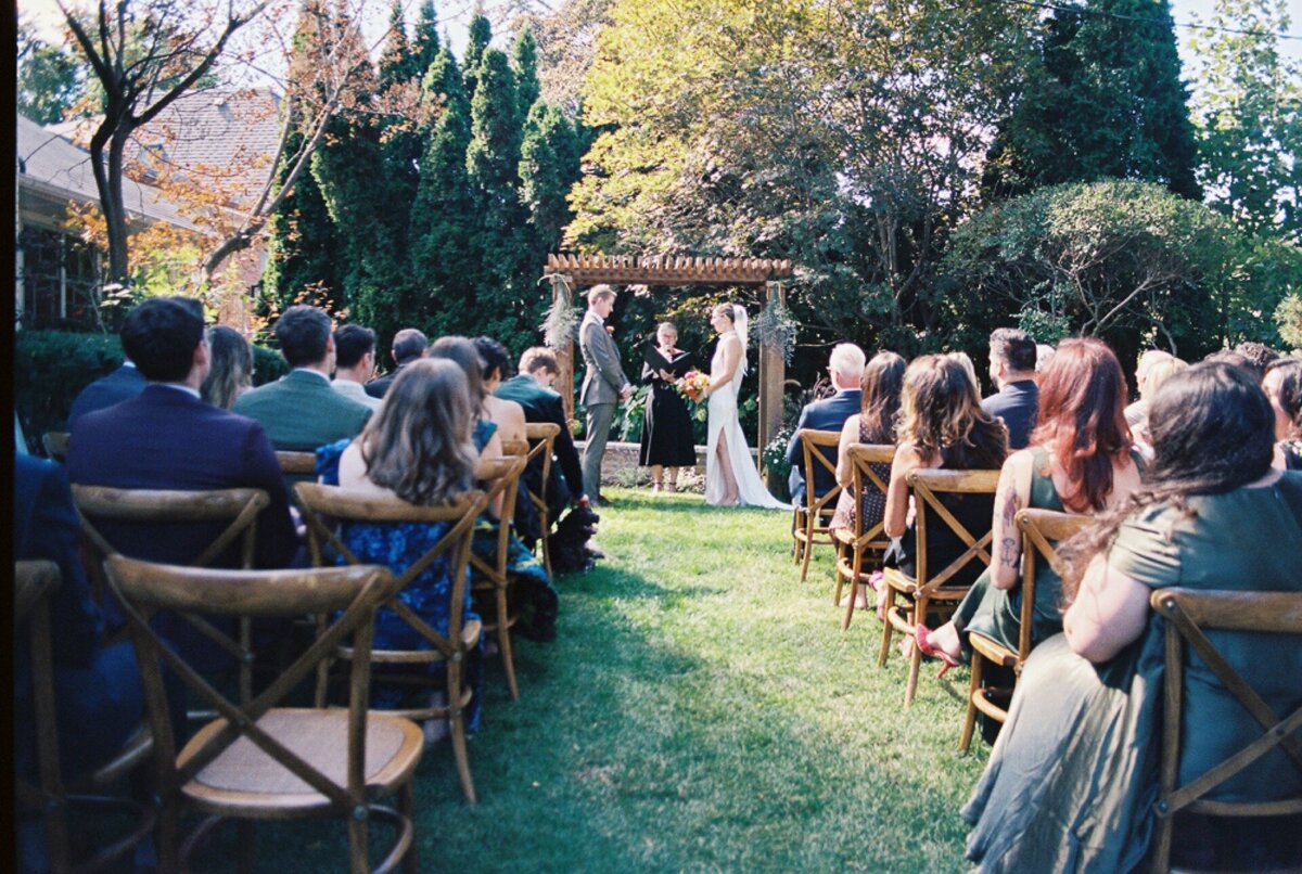 Groom holding the hand of his bride while exchanging vows at their backyard wedding ceremony