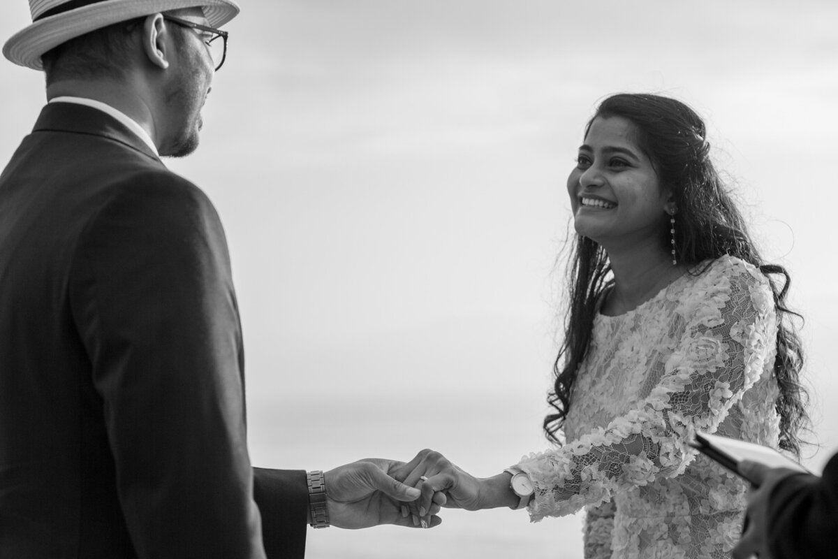 A bride smiles at her groom as the hold hands during their elopement ceremony.