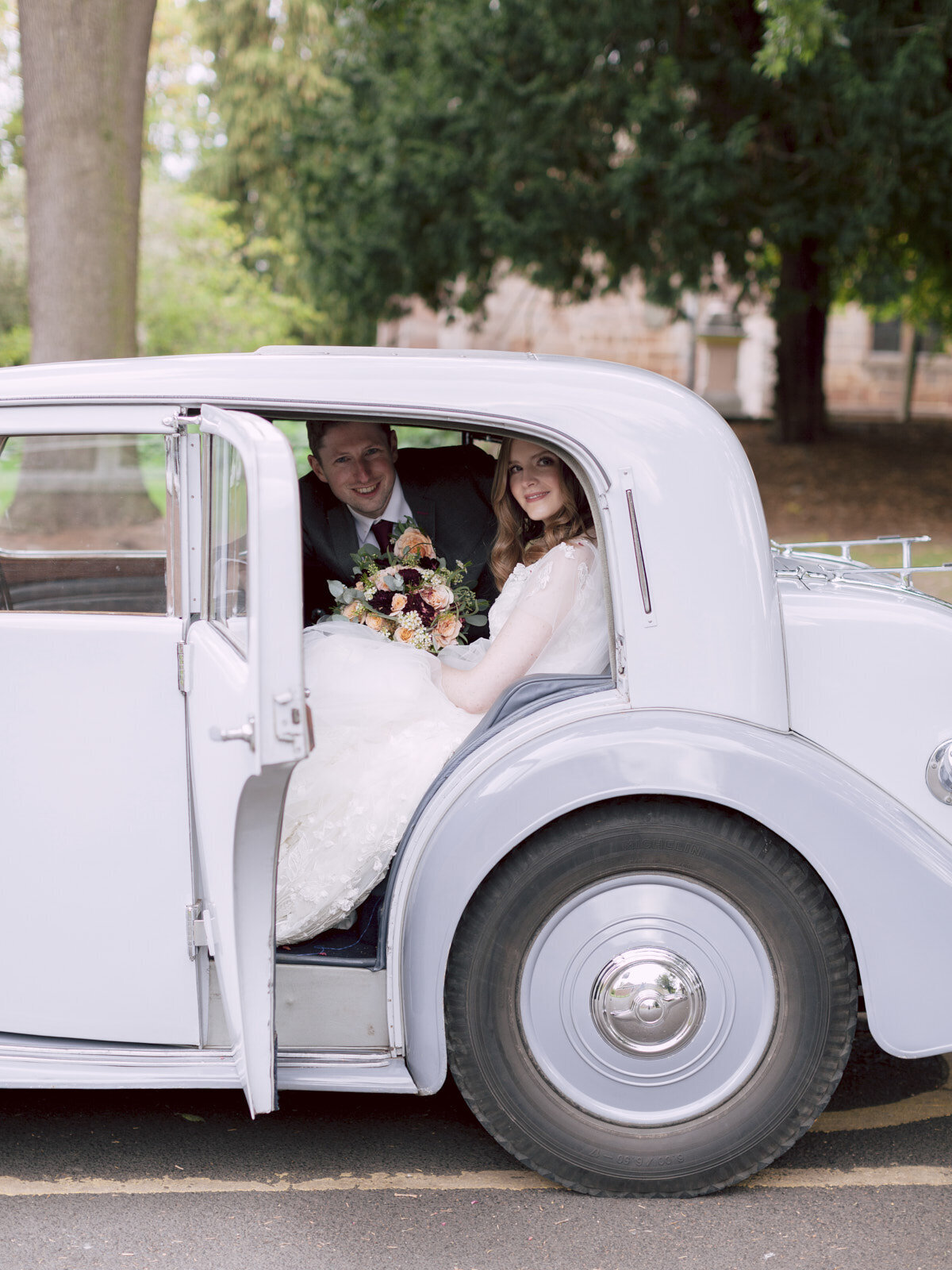 bride and groom sitting in the  vintage wedding car and posing for photo