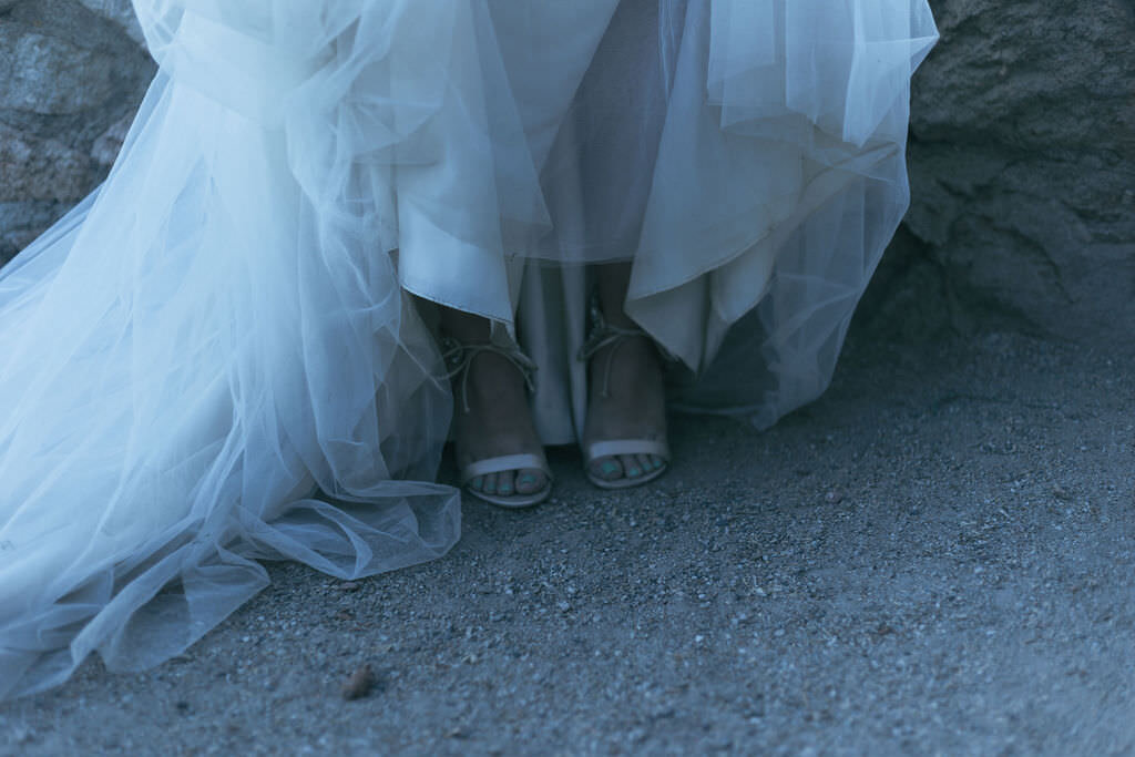 A close up views of a person's shoes under their wedding dress.