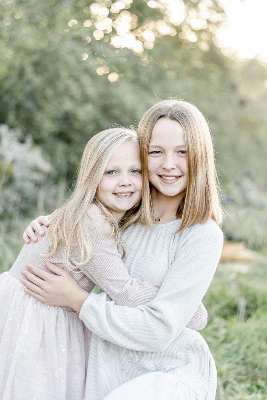Two blond sisters hug in a filed at South 40 Farm in Franklin TN by Nashville family photographer Kristie Lloyd