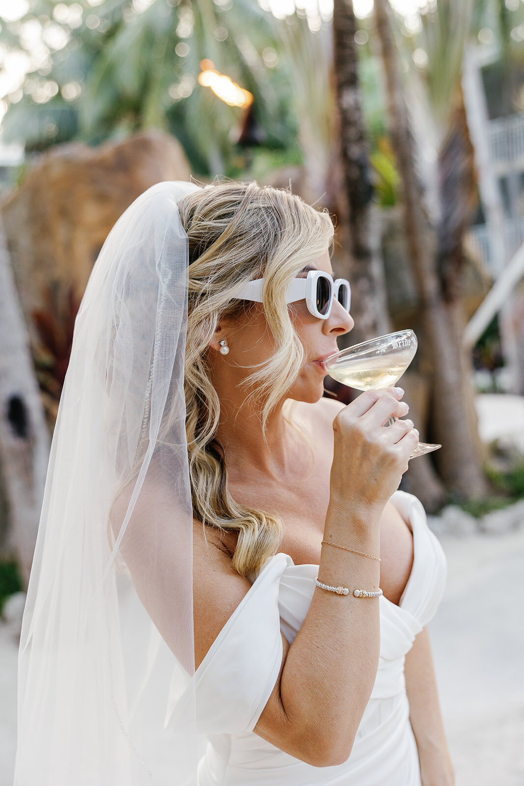 Monica enjoys a celebratory champagne toast while wearing chic white sunglasses at her Casitas at Cheeca wedding.