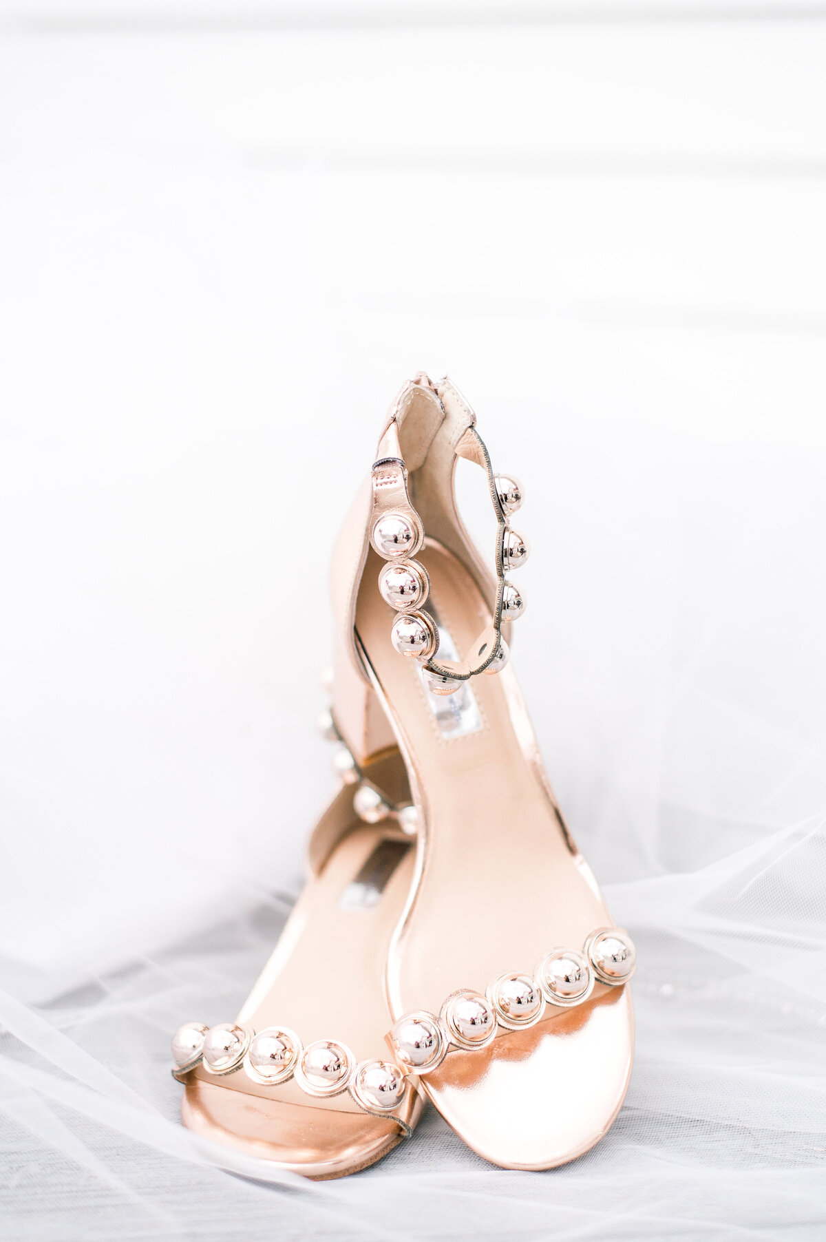 wedding shoes stacked on top of eachother with the veil flowing