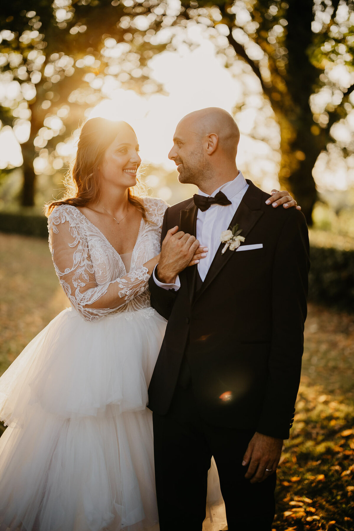 Bride and groom smiling at sunset among trees of Villa Corsini Mezzomonte, wedding photographer Tuscany Florence.