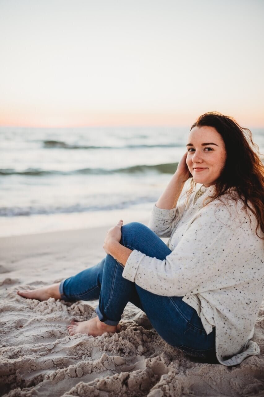 brittney, sitting and smiling on panama city beach at sunset