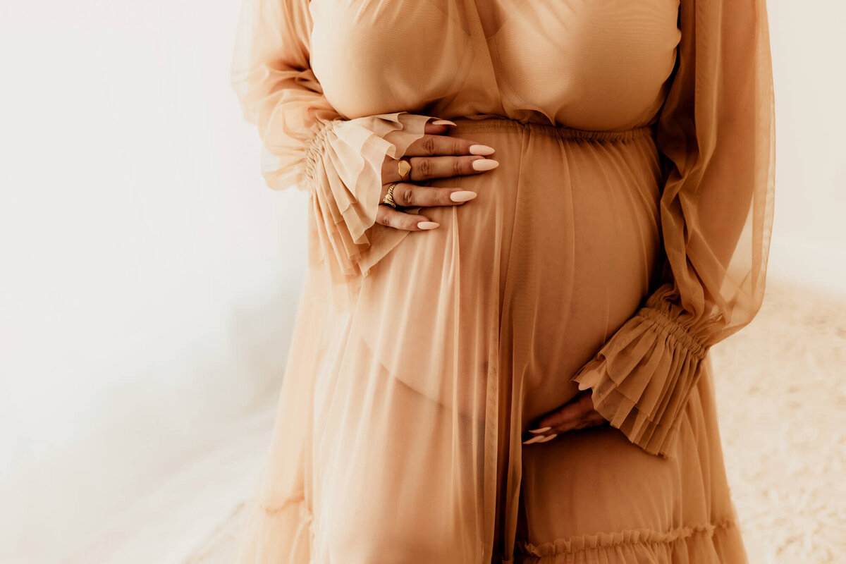 Woman holds her baby bump.