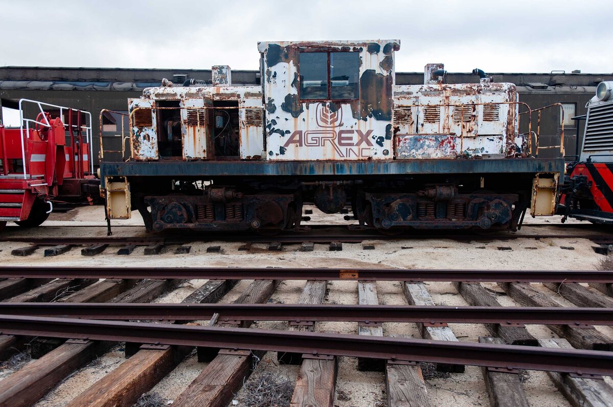 A rusted Agrex train car with old tracks in the foreground