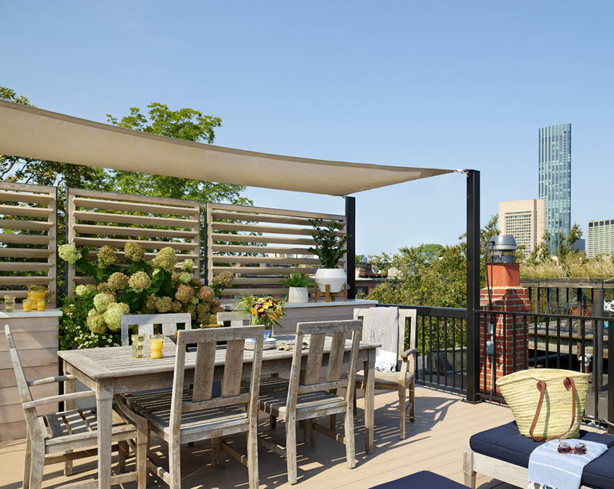 A rooftop deck with a custom trellis, sailcloth sun protection, and weathered teak furniture offers perfect views of the Boston skyline. Boston goals. By Sarah Scales.