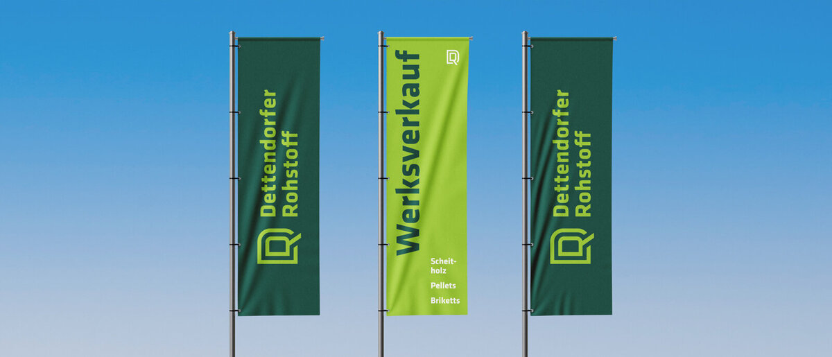 Rebranding für Dettendorfer Rohstoff – neue Markenidentität mit Logo auf Fahnen vor blauem Himmel.
