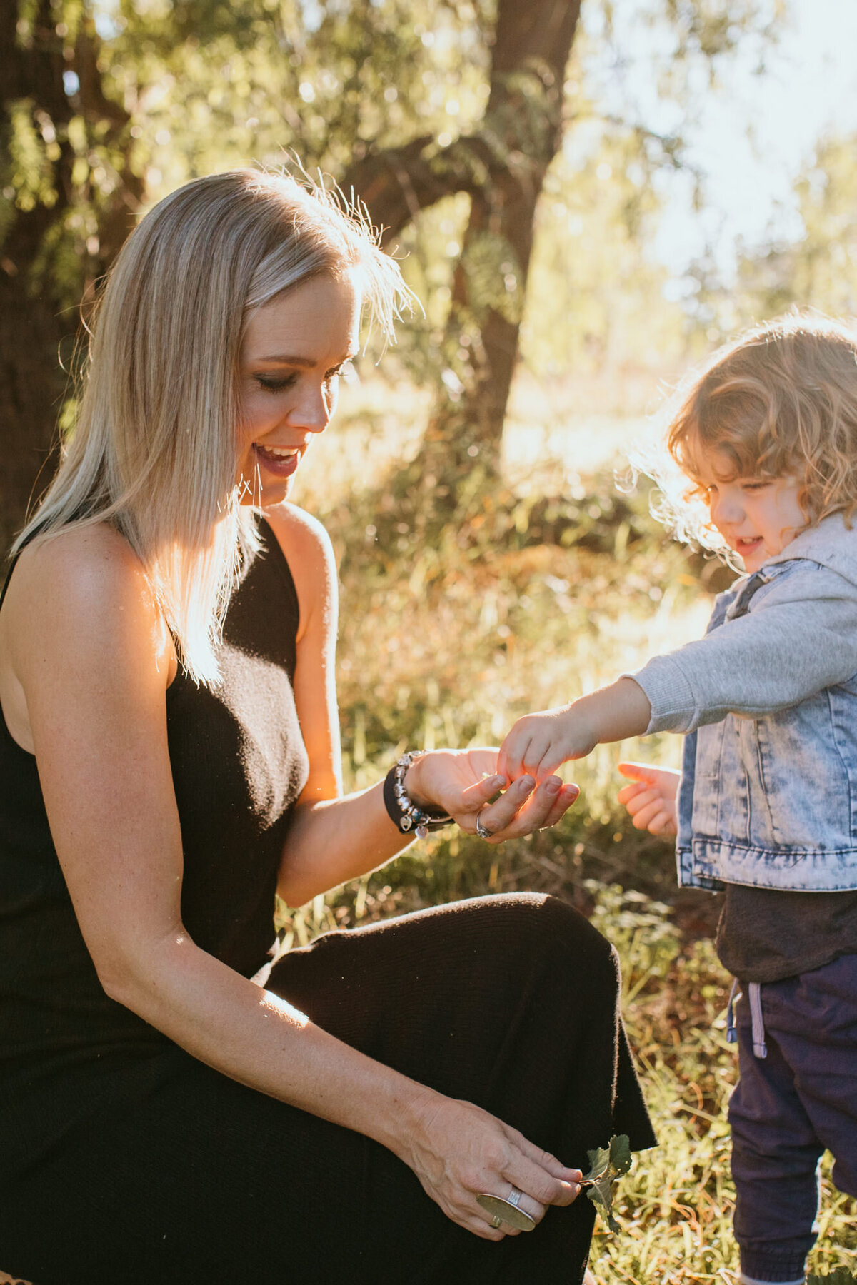 Mother & son share an intimate moment in the sunset, looking at tiny pieces of grass. 