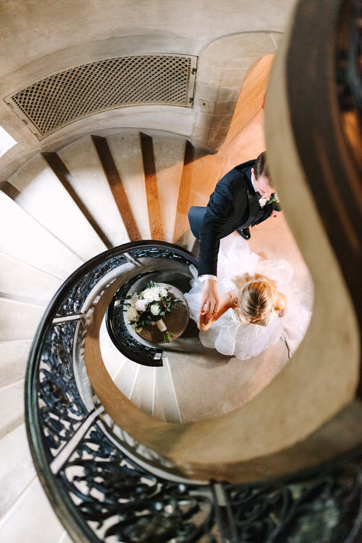 groom spins bride at the bottom of spiral stair case