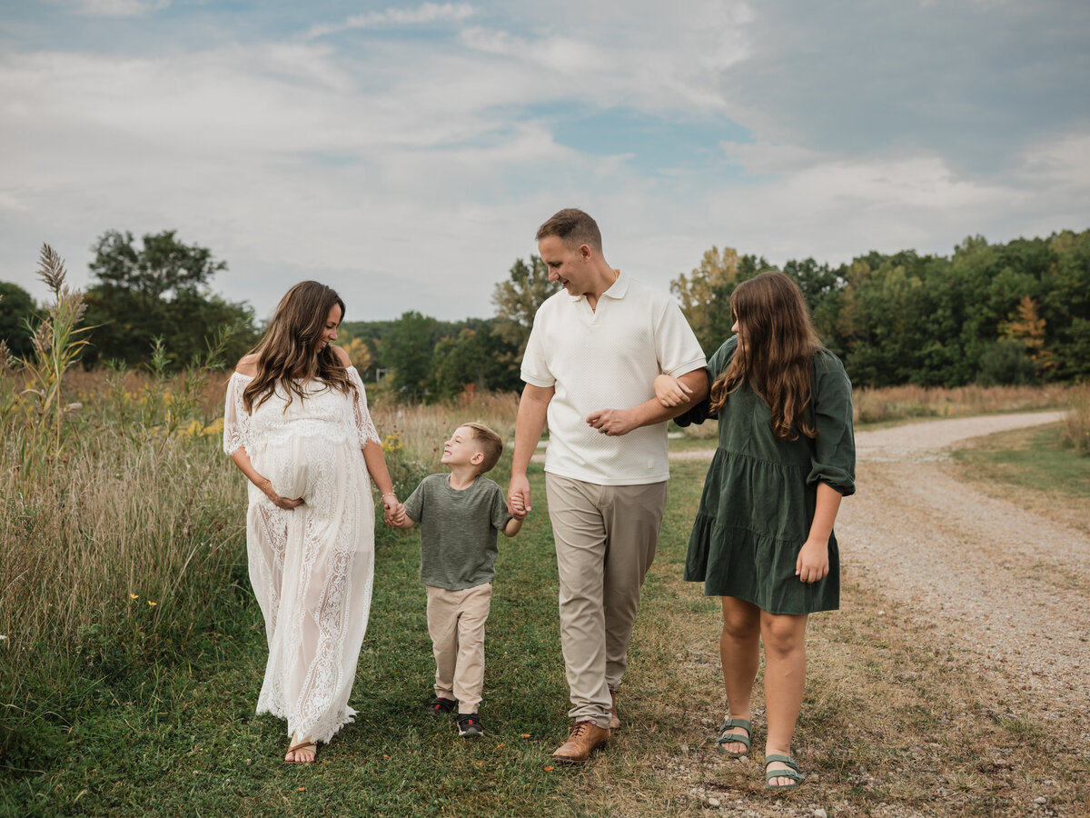 parents holding hands with two children walking in park cleveland maternity photographer