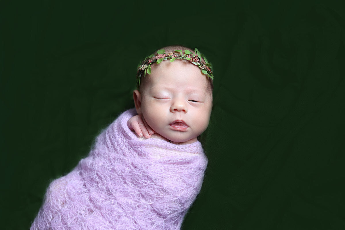 Newborn baby wrapped in knitted purple blanket at home photo session in Calgary Alberta