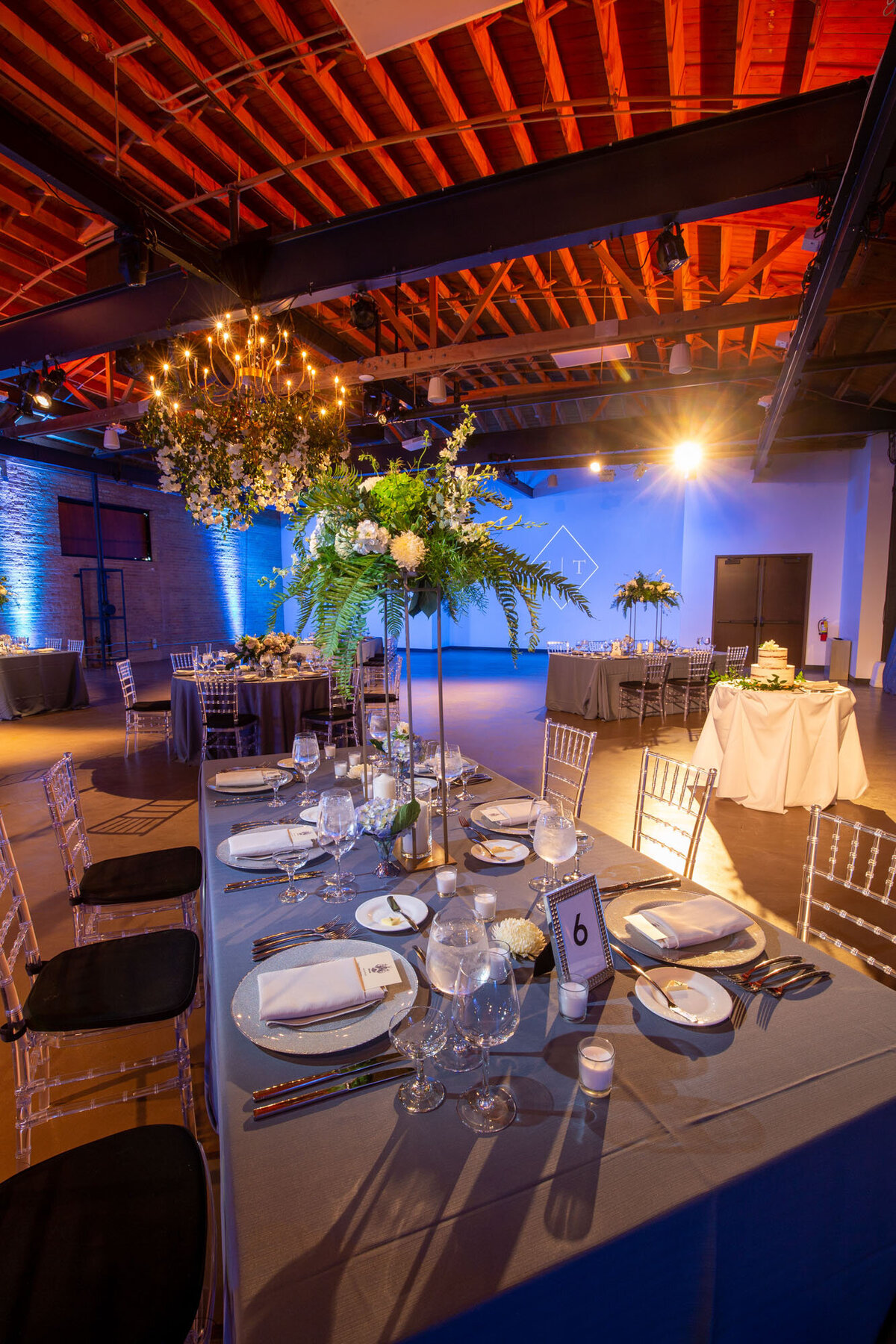 A large room with tables and chairs and flowers hanging from the ceiling