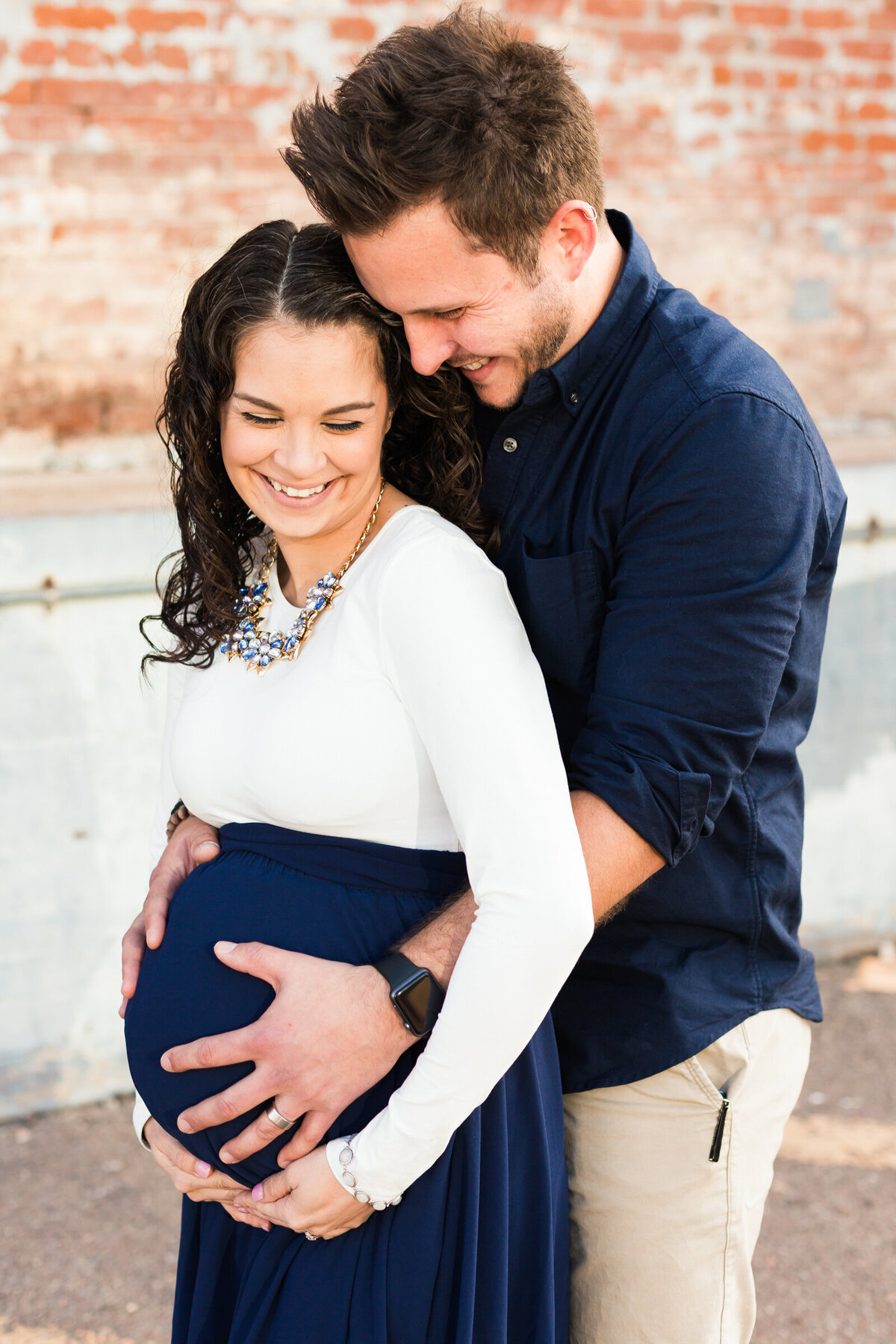 mom and dad to be posing for maternity photo in downtown Phoenix