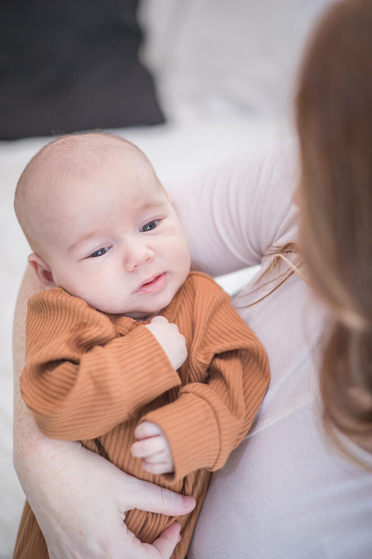 newborn baby boy dressed in rusty brown clothes in moms arms