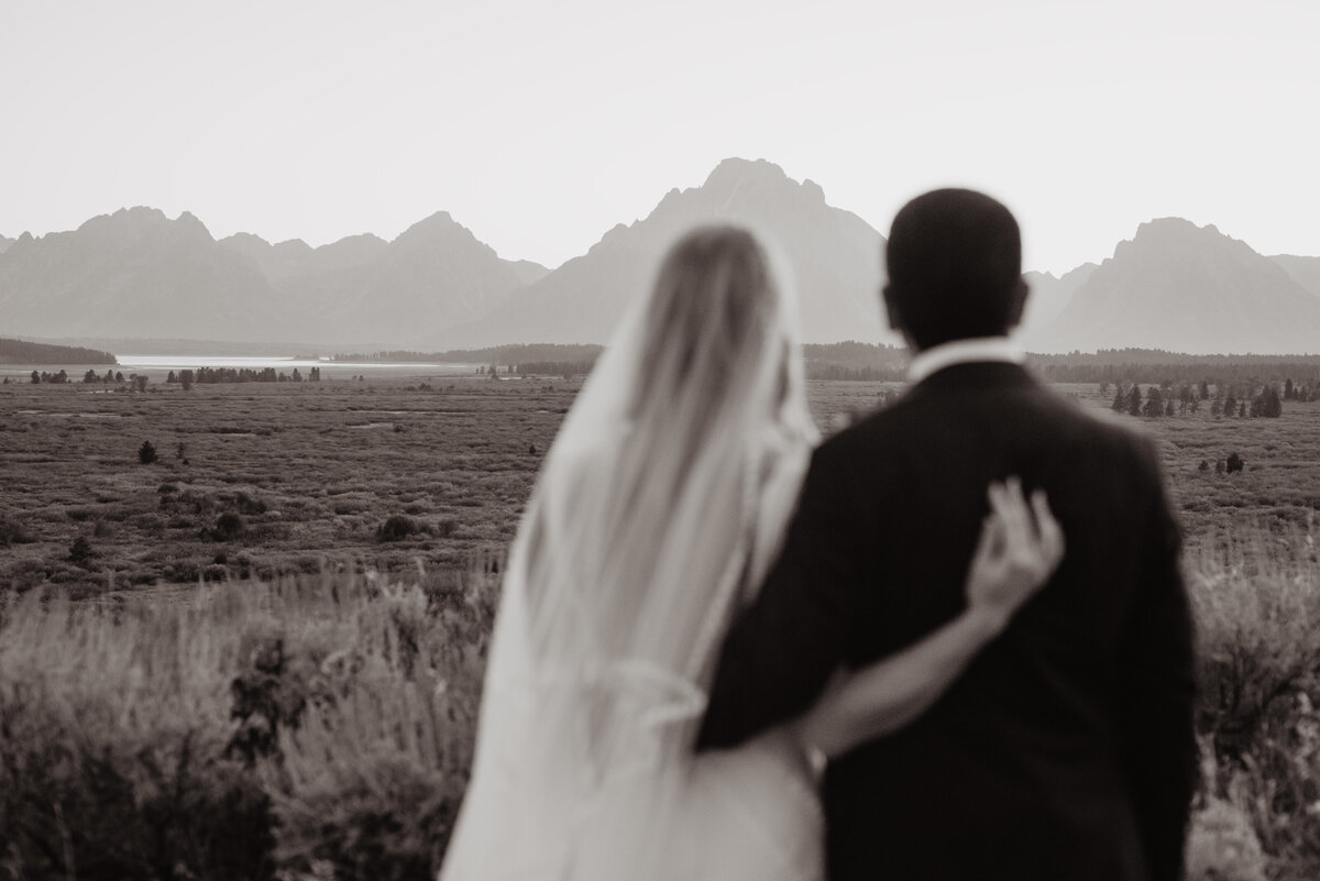 Photographers Jackson Hole capture bride and groom looking at Tetons