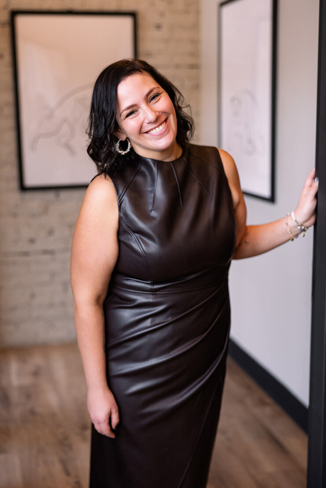 Woman smiling with her hand on the wall in a brown dress
