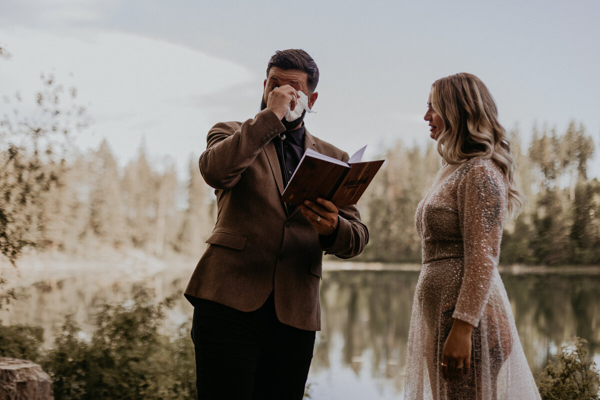 groom wiping tears while reading vows