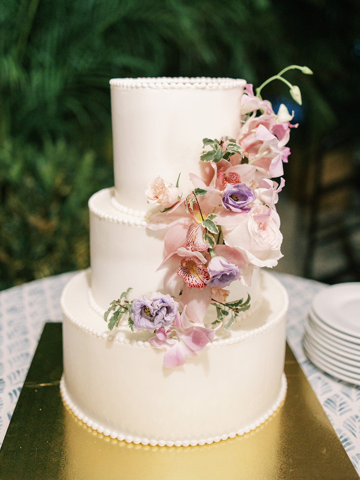 Lush tropical cake flowers for private estate beach wedding. Destination wedding florals in orange, pink, dusty blue, lavender, peach, and blush in Exuma, Bahamas. Floral Design by Rosemary & Finch Floral Design.