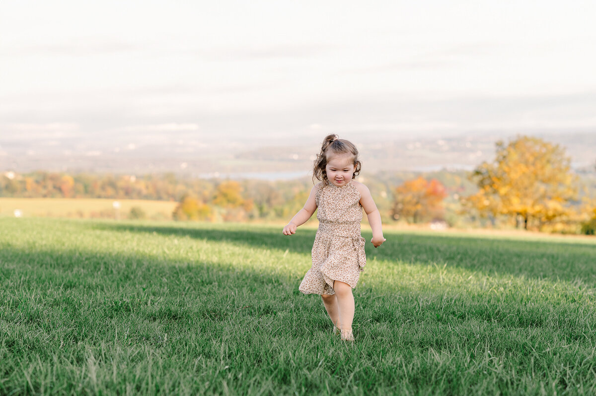 girl running up hill during session at sam lewis state park york pa family maternity newborn photographer